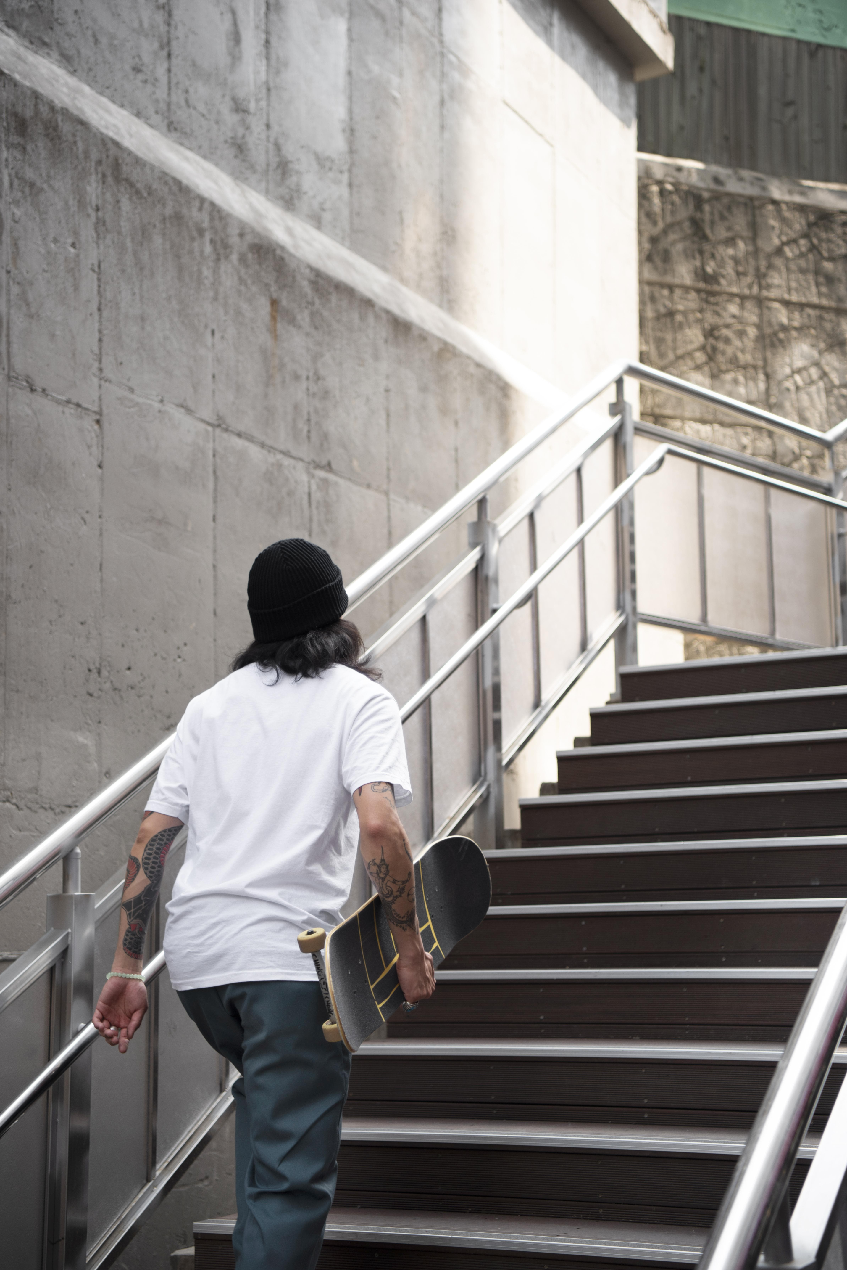 3._asian-man-holding-his-skateboard-while-walking-stairs_1.png